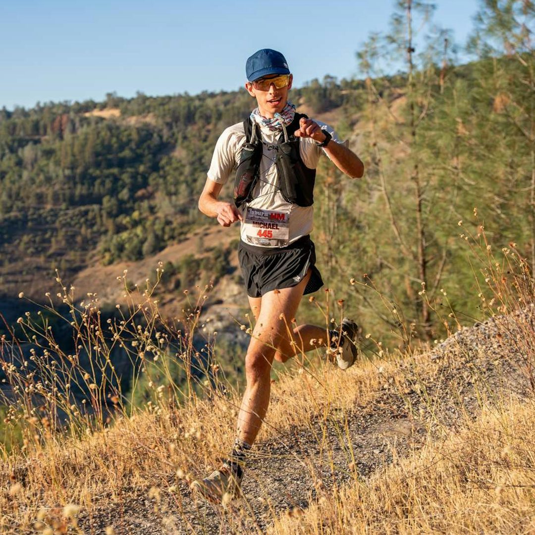 Trail runner on rocky mountain terrain, where secure storage and light layers matter more than on the road