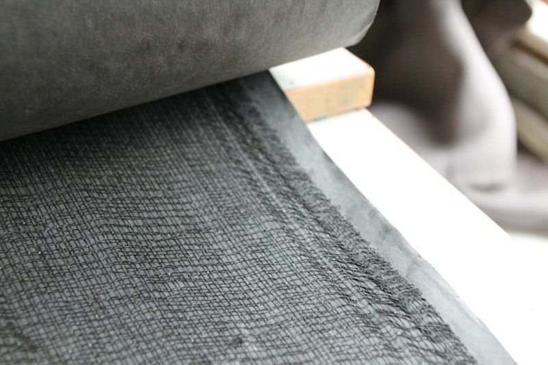 Close-up of an open black mesh textile with a visible grid structure and light passing between the woven threads
