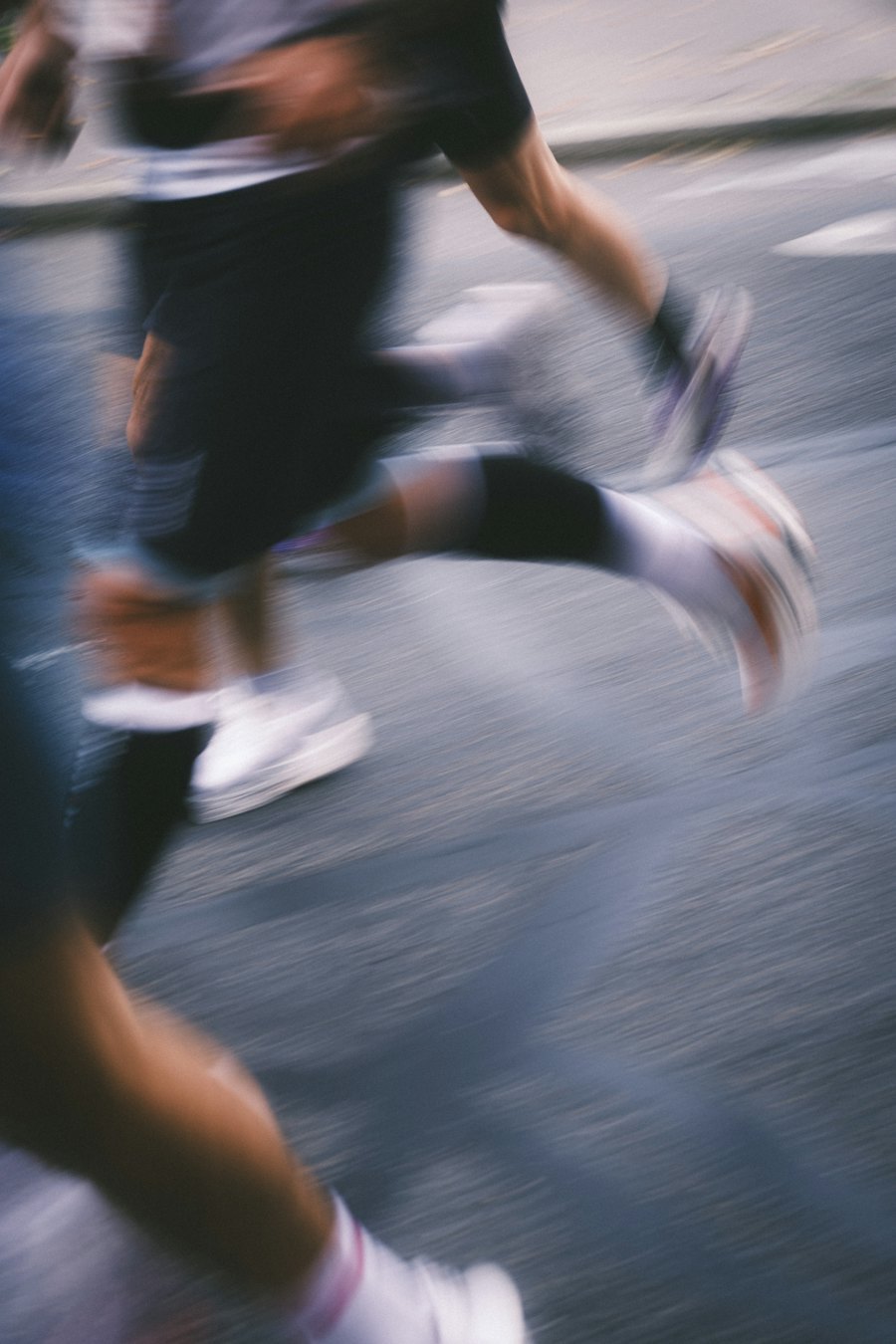 Runners in motion during a road race wearing lightweight performance running tops