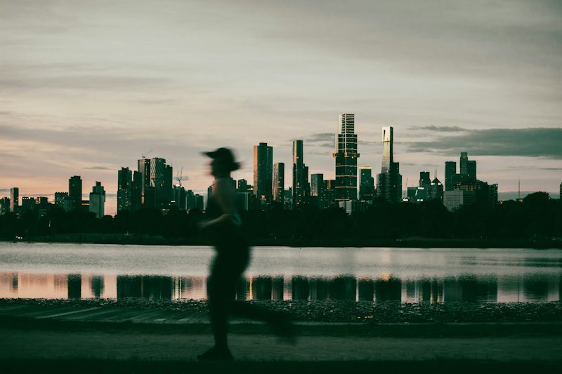man running with a city skyline behind him