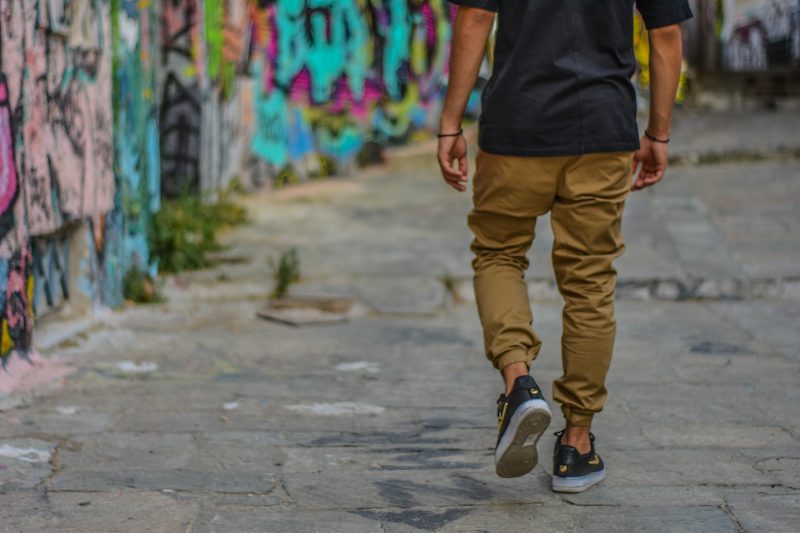 man walking beside a wall with graffiti