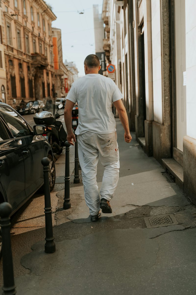 man walking down a street next to parked cars