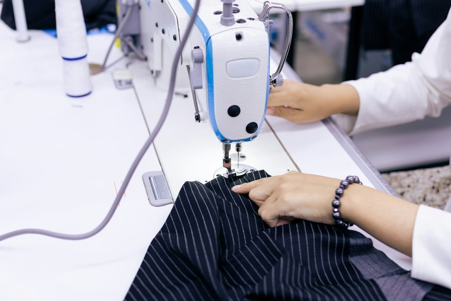 Hands guiding fabric through a sewing machine during garment construction