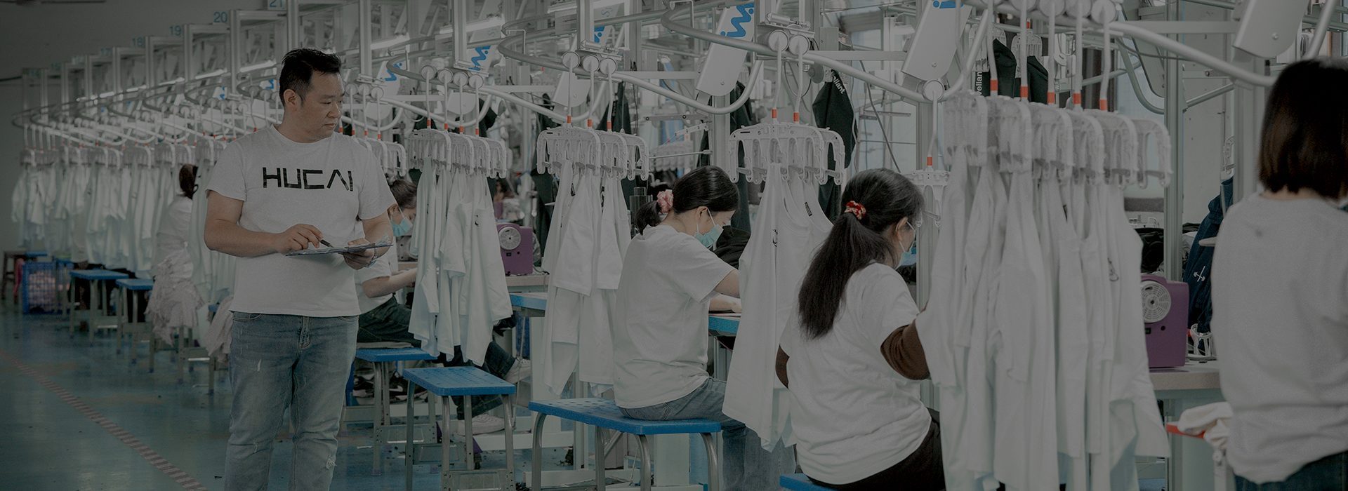 Production floor at the HUCAI activewear factory with hanging garment racks and sewing stations