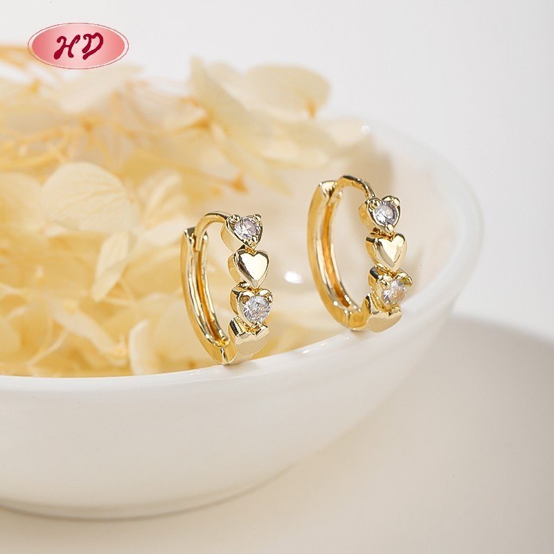 Clear CZ heart huggie earrings styled on floral background - Hengdian HD Jewelry
