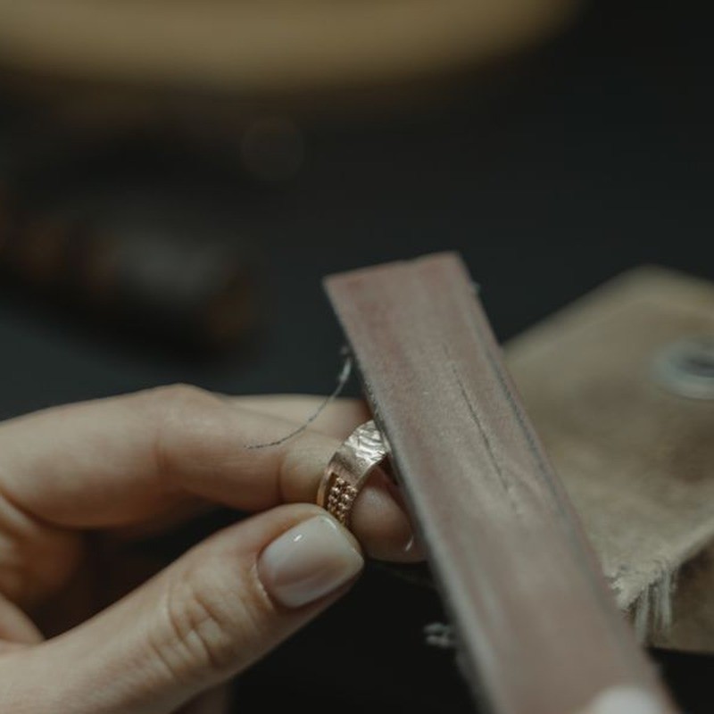Craftsman polishing a gold plated ring to restore cubic zirconia shine