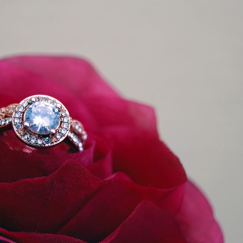 Gold cluster ring with clear cubic zirconia stones on a red rose, illustrating styled product photography for digital catalogs