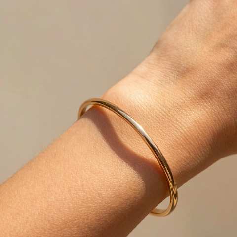 Brazaleta chapada en oro en una muñeca a plena luz de verano