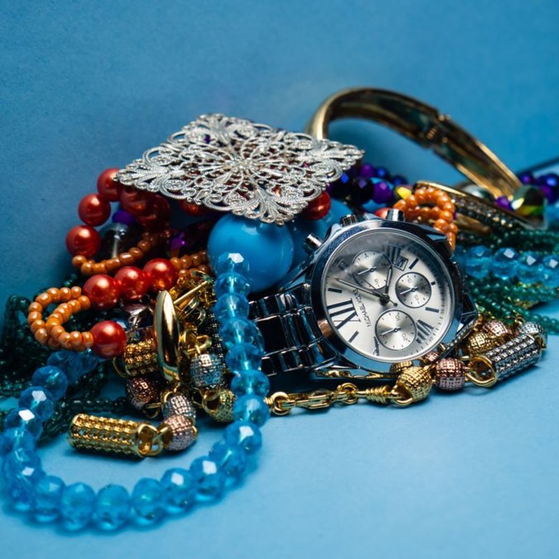 Colorful costume jewelry collection on blue background — mixed beads, chains, bracelets and brooches representing variety in wholesale