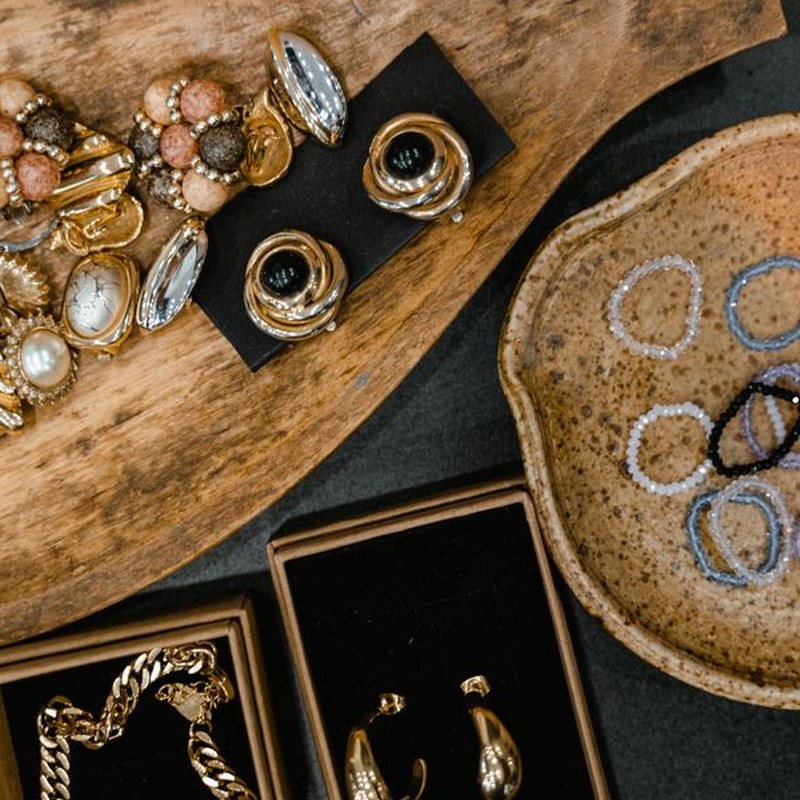 Handmade gold jewelry displayed on wooden board and ceramic trays with gift boxes — presentation and packaging showcase