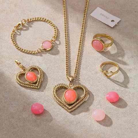Flat lay of 18K gold plated jewelry set with coral pink accent stones