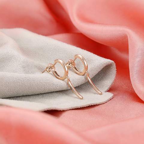 Pair of 18K gold plated earrings on a soft cleaning cloth over a coral silk backdrop, gentle care concept