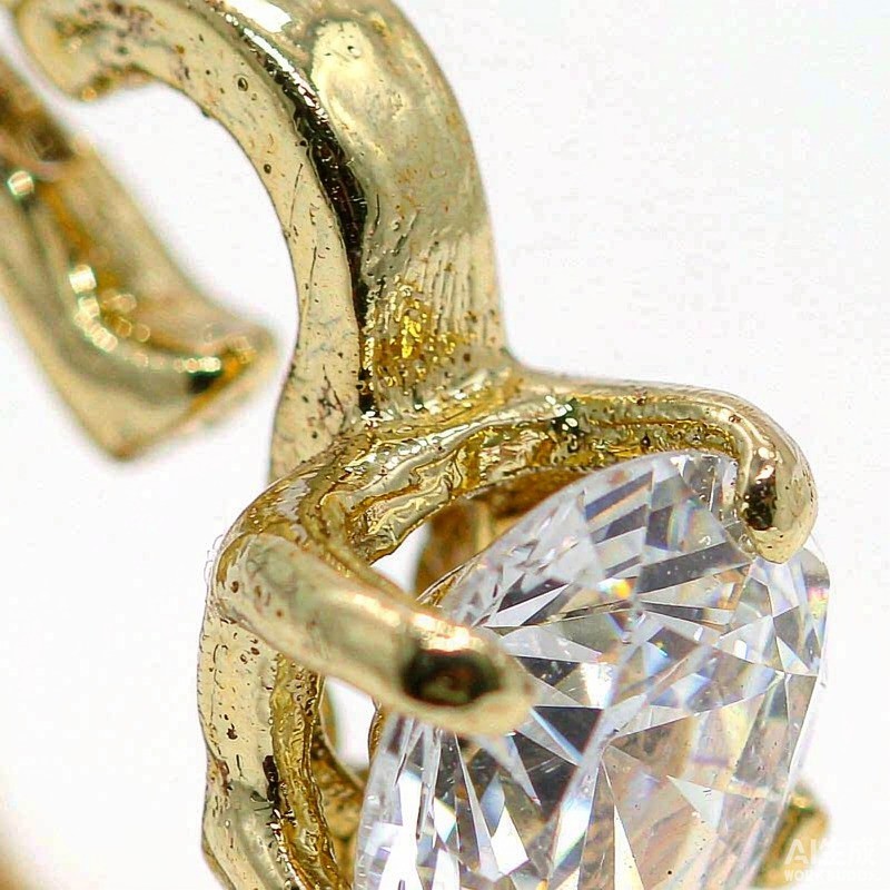 Macro close-up of a gold-plated ring with an AAA cubic zirconia stone, showing faceted sparkle and polished metal
