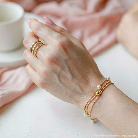 Close-up of a hand wearing stacked gold plated rings and a bracelet