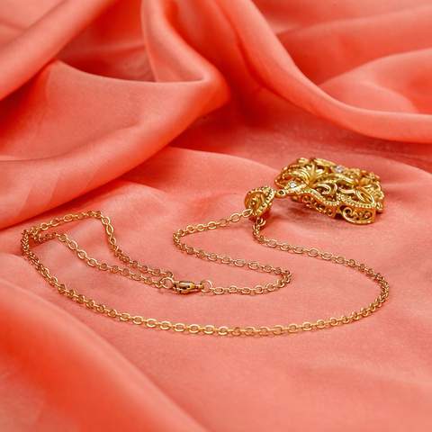 Gold plated pendant necklace displayed on coral pink silk