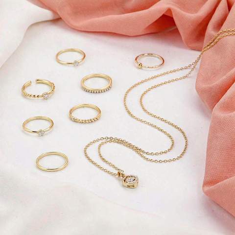 Gold plated fashion jewelry arrangement on a white surface with a coral accent