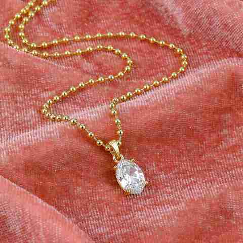 Gold plated CZ necklace in bright condition kept on coral pink velvet