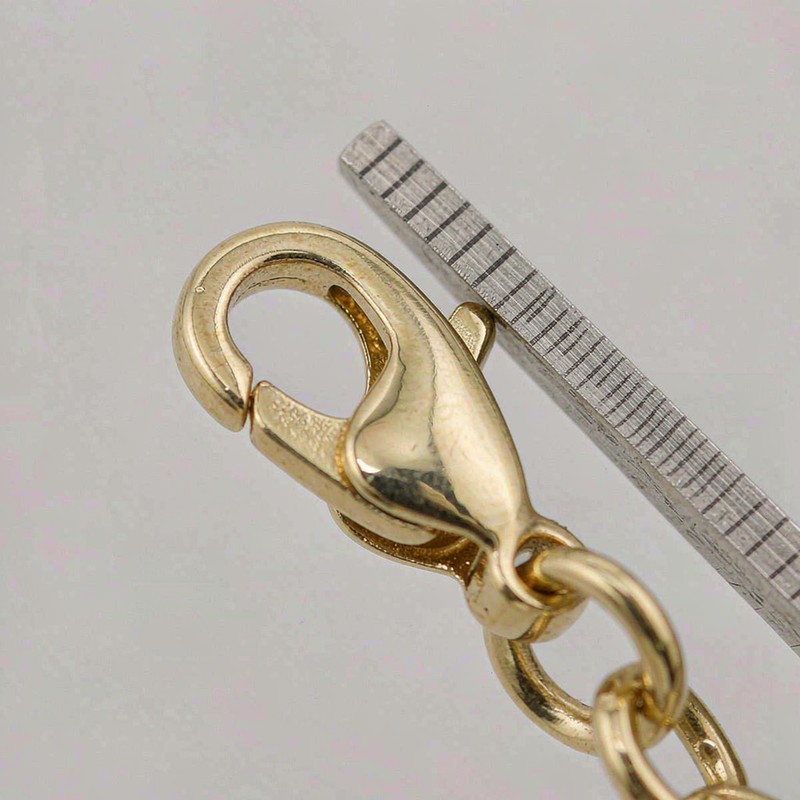 Broche de langosta chapado en oro 18K junto a un medidor de precisión durante la inspección de calidad