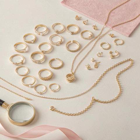 Assorted gold plated jewelry pieces arranged with a jeweler's loupe for plating inspection