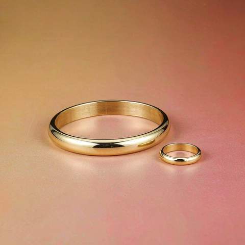 Gold plated bangle and ring on a warm gradient surface showing even plating finish