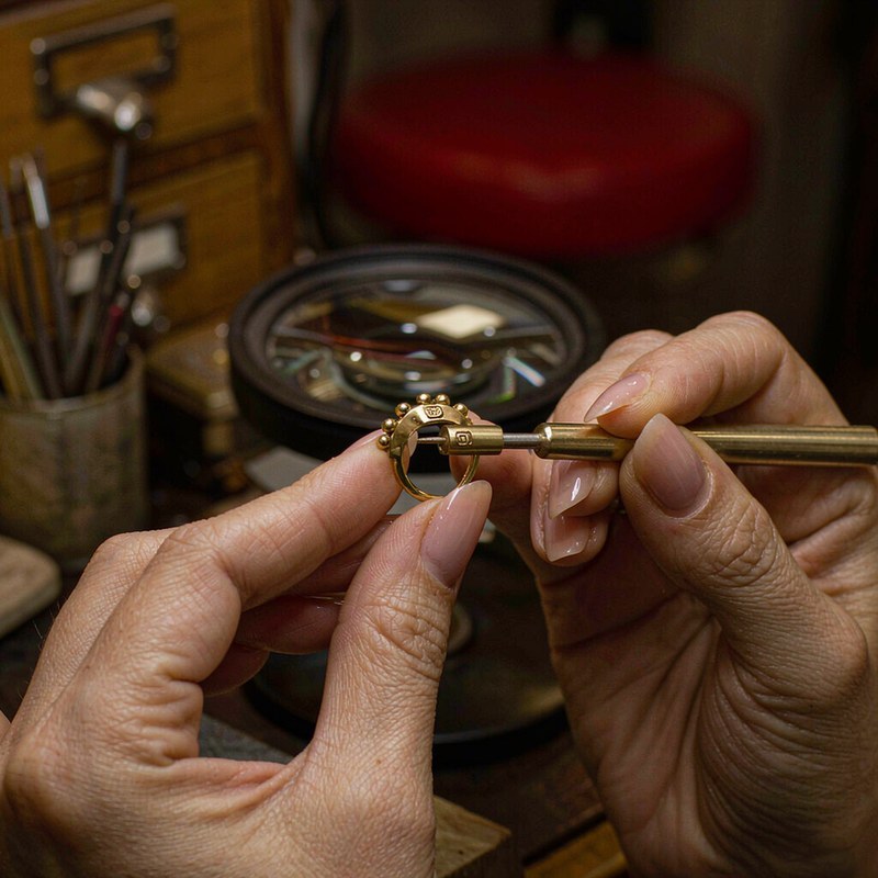 Jewelry quality inspector checking an engraved stamp on a gold plated ring through a loupe
