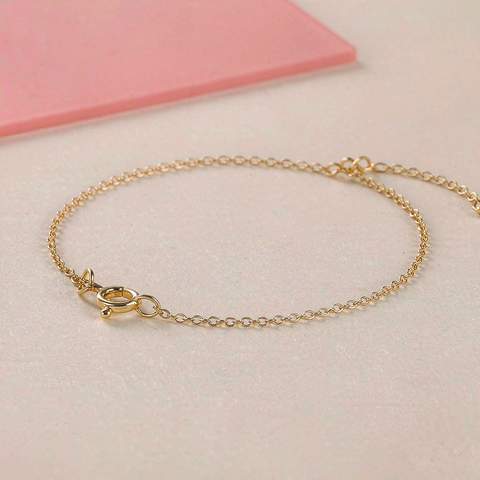 Delicate gold plated bracelet with clasp on a neutral surface