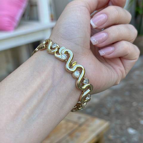 Hand wearing a gold plated bracelet set with cubic zirconia stones