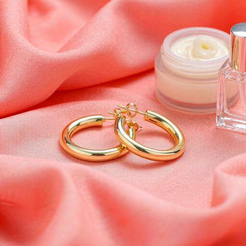 Gold plated hoop earrings beside cosmetic cream and perfume, common sources of residue
