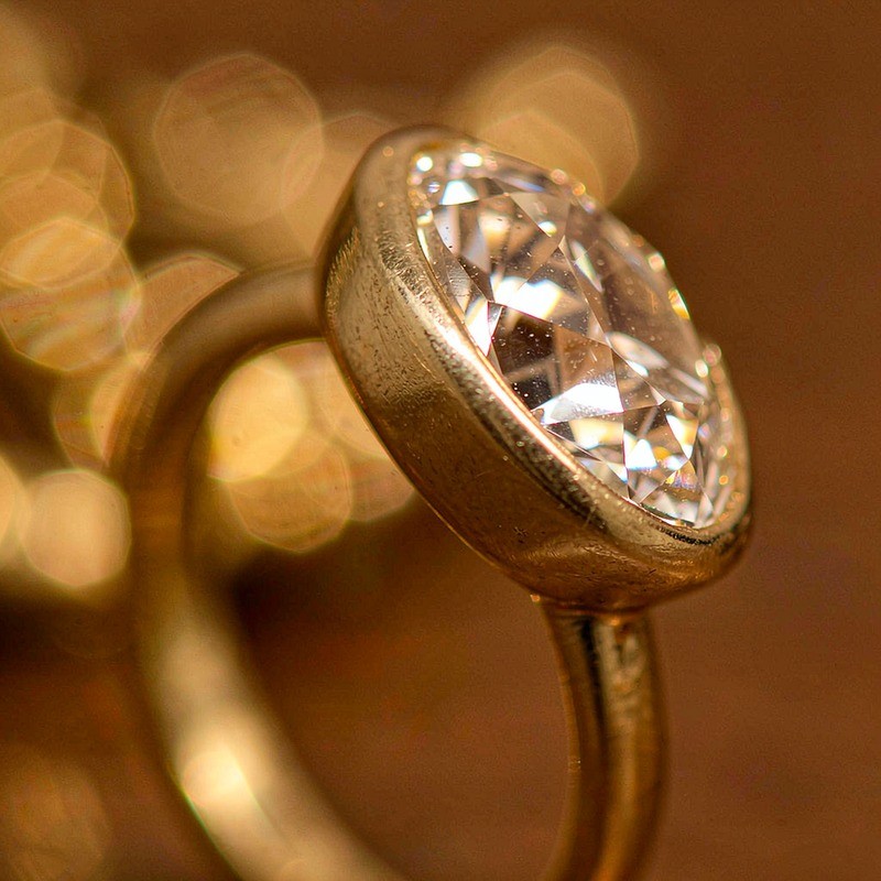 Macro detail of an 18K gold plated brass ring showing the smooth gold-toned surface and a clear AAA cubic zirconia in a bezel setting