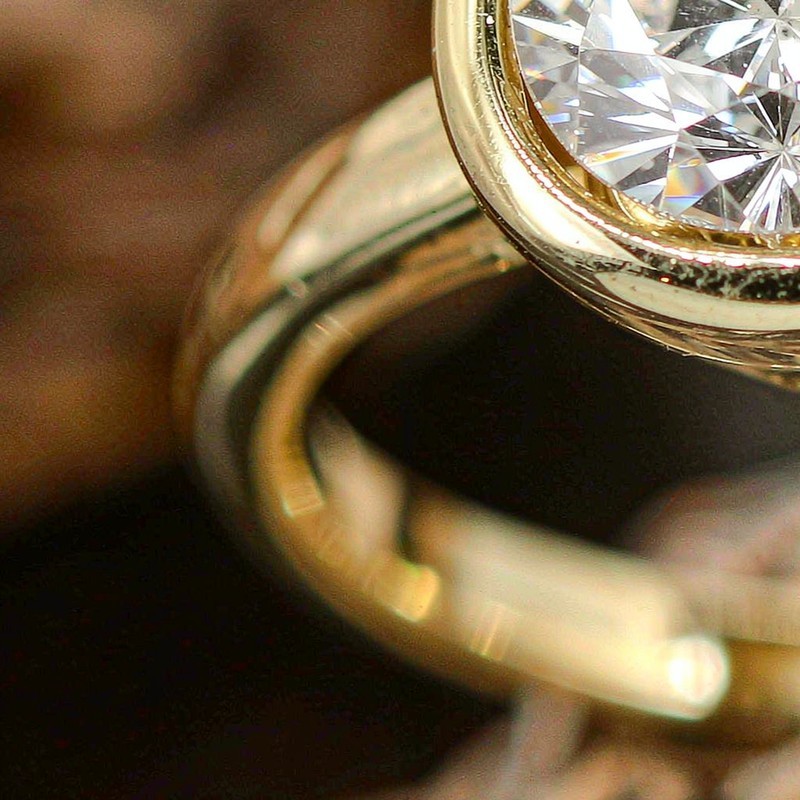 Macro detail of an 18K gold plated brass ring with a clear AAA cubic zirconia stone, showing polished craftsmanship