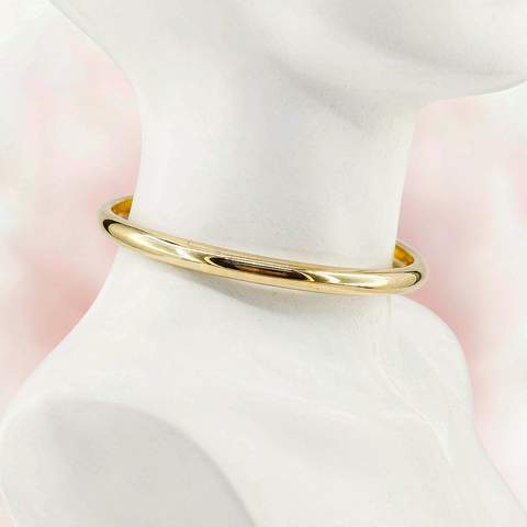 Gold plated bangle displayed on a white jewelry stand