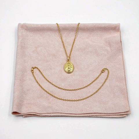 A freshly cleaned gold plated pendant necklace and bracelet laid flat on a soft pink cloth to dry