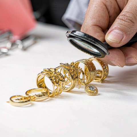 Inspector using a loupe to check gold plated rings before shipping