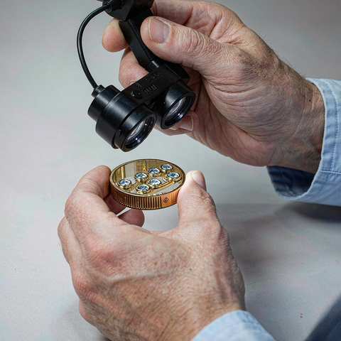 Quality inspector checking a gold plated ring under a magnifier