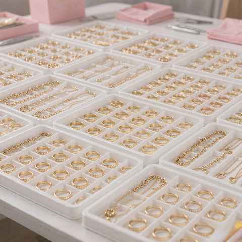 Rows of gold plated jewelry organized in production trays for a bulk order