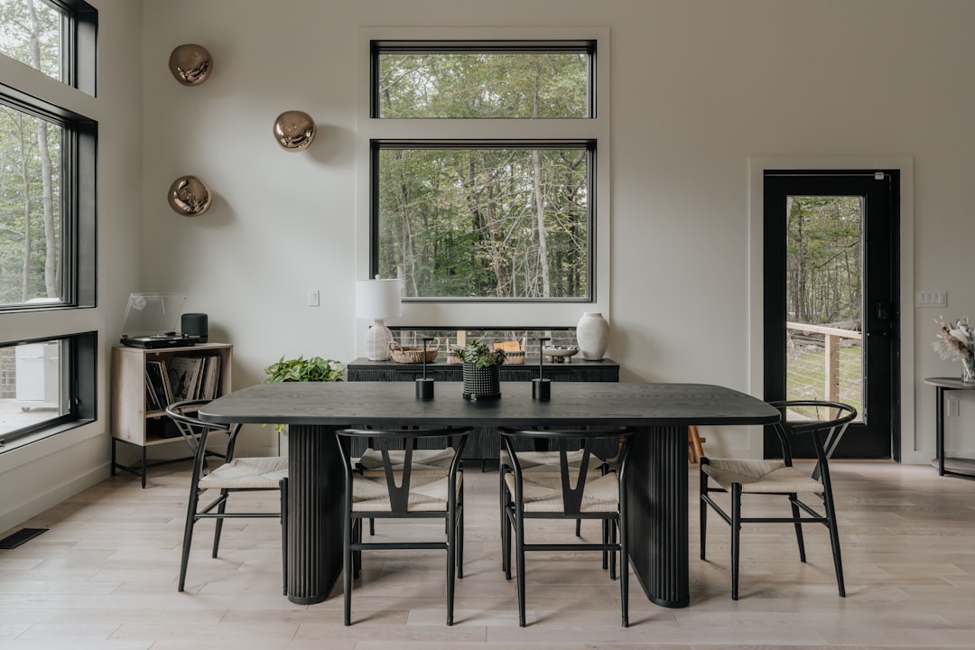 A modern dining room with a large wooden table supported by black metal spider legs