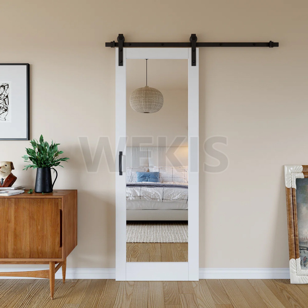 Mirror barn door closed against a bedroom wall with black sliding track
