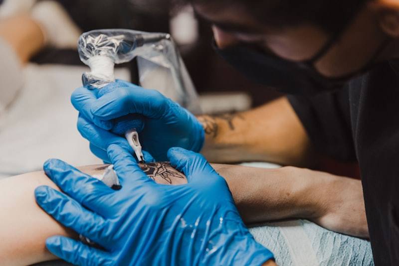 PMU artist with blue gloves performing tattoo procedure