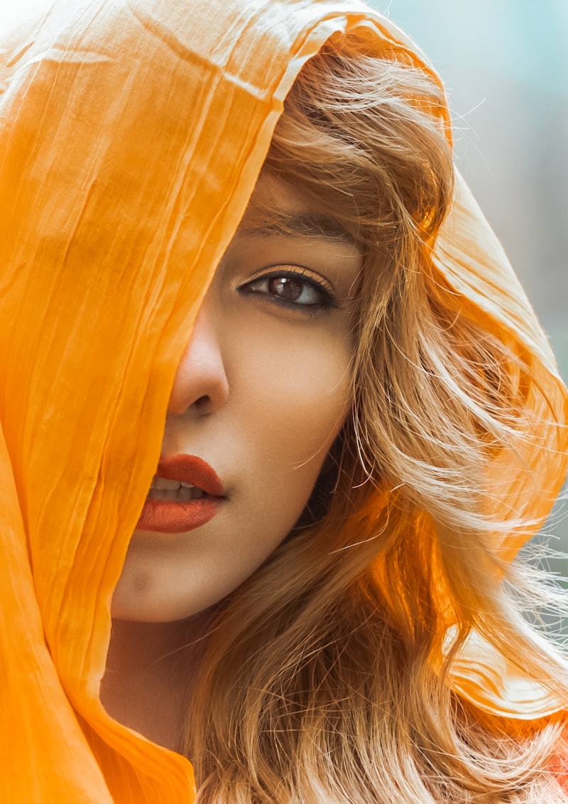 Fashion model portrait with orange silk fabric covering