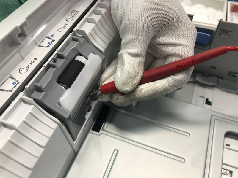 Technician repairing printer with gloves in workshop
