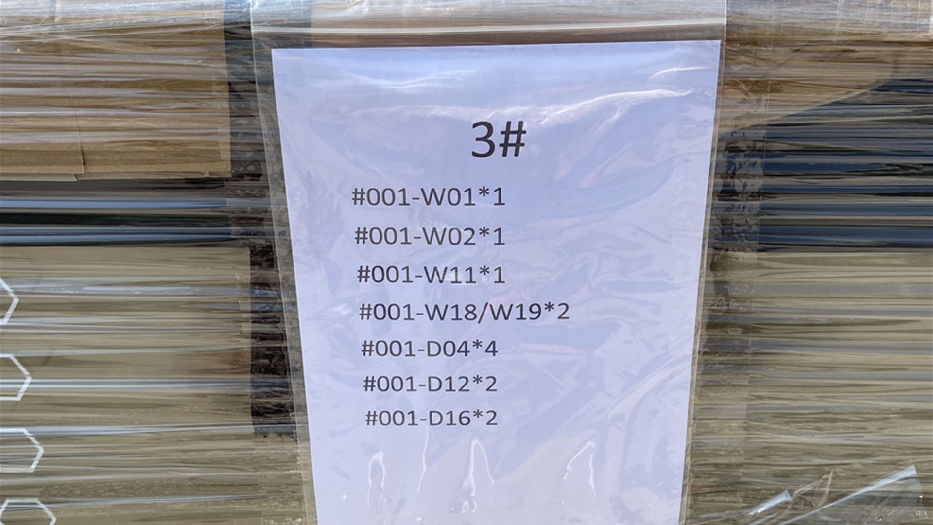 Close-up of a printed packing list attached to a wrapped window and door bundle