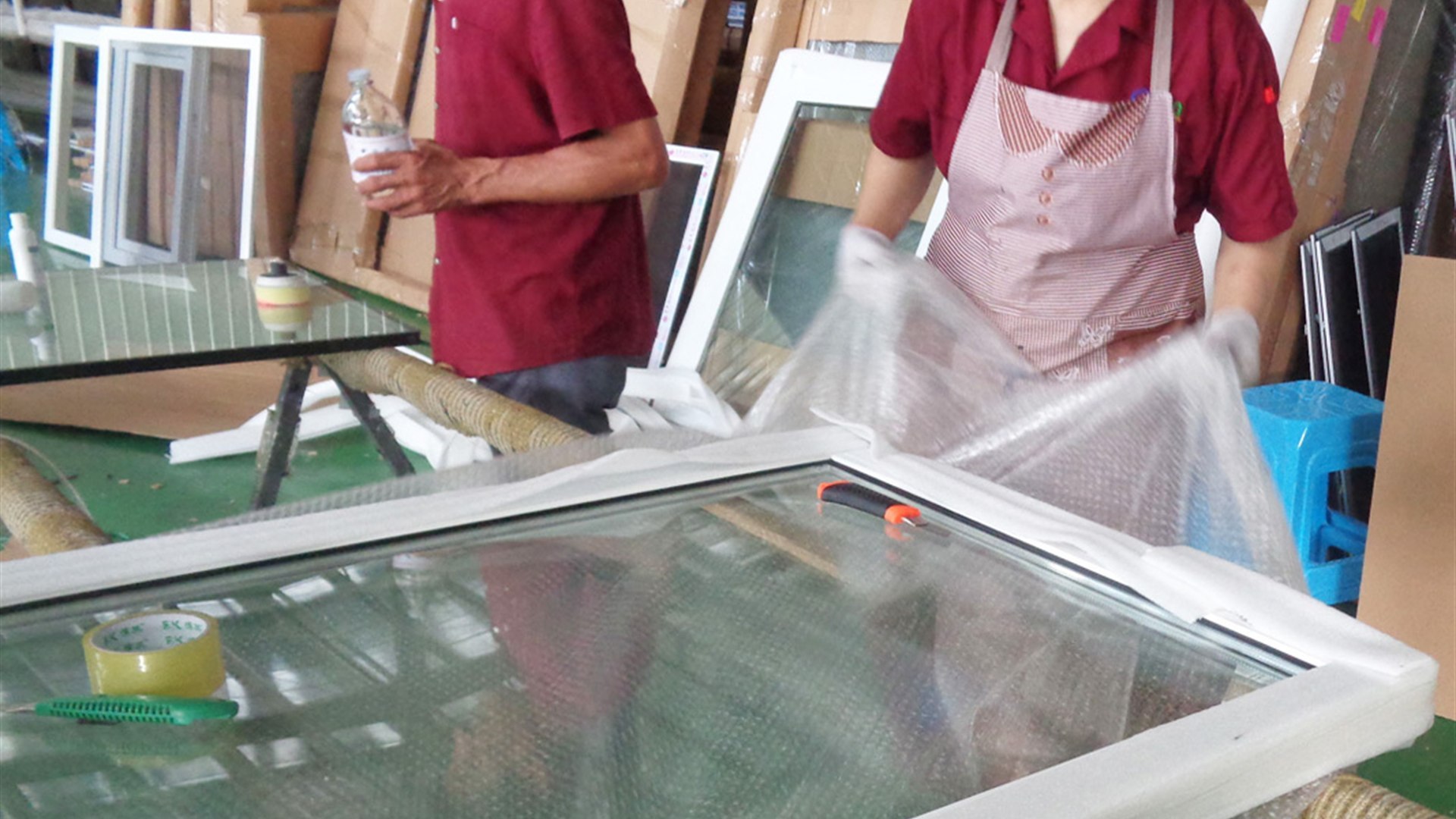 Close-up of protective film wrap and corner strips on an aluminium window frame