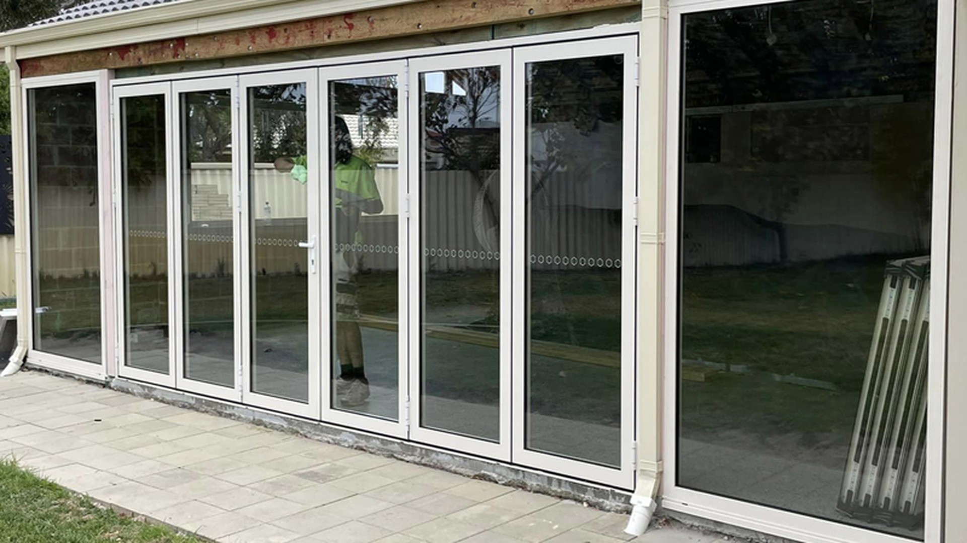 A multi-panel folding door installed across a veranda opening, photographed closed along its running track.
