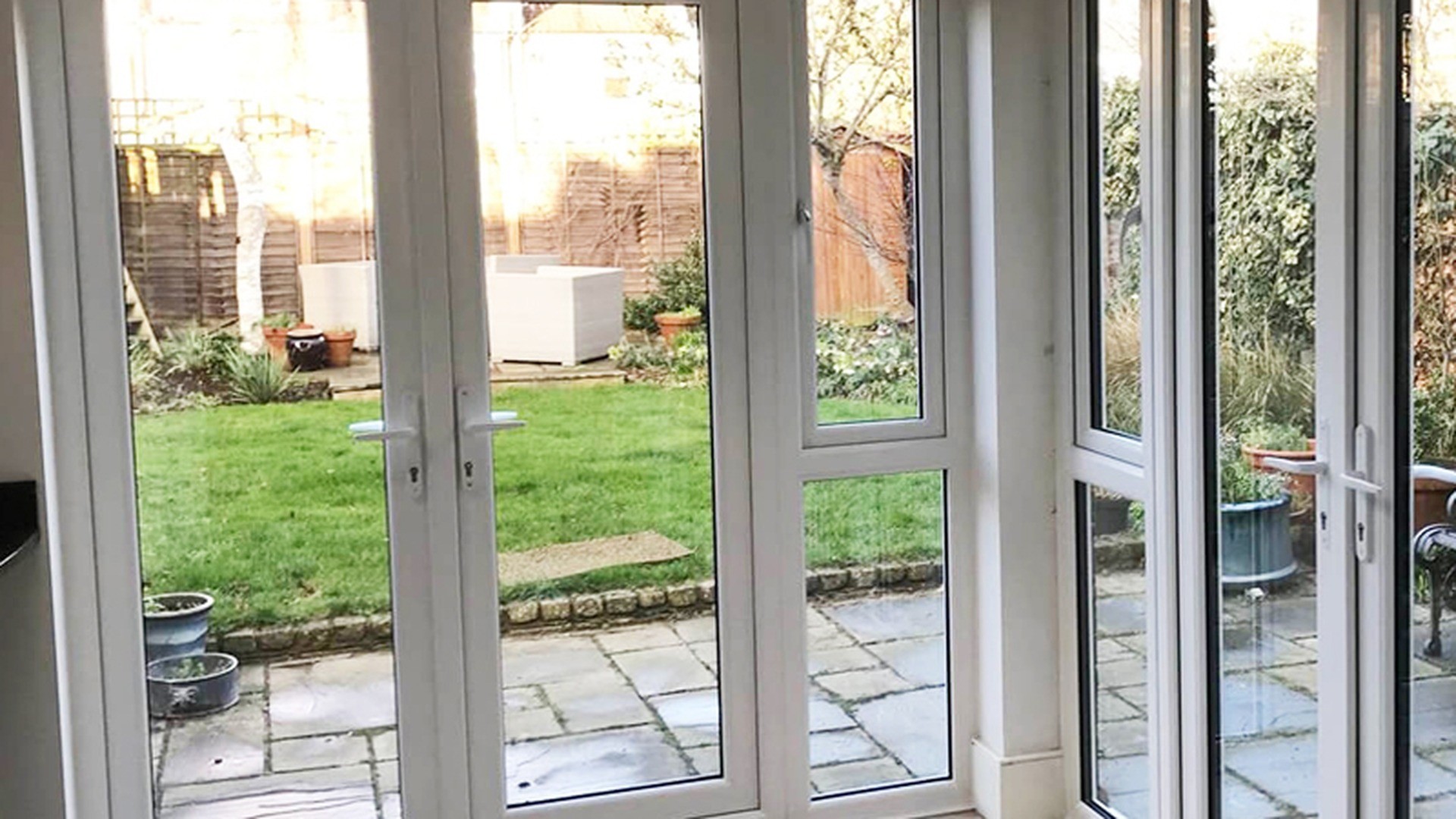 Full-height uPVC glazing in a finished residential project, opening onto a garden terrace.