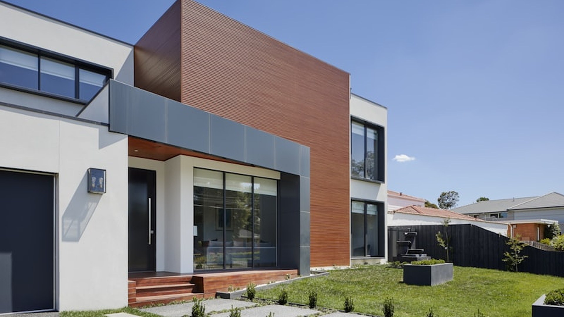 A finished residential elevation with large sliding glazed openings and fixed windows, the openings where hardware and glazing carry the security specification.