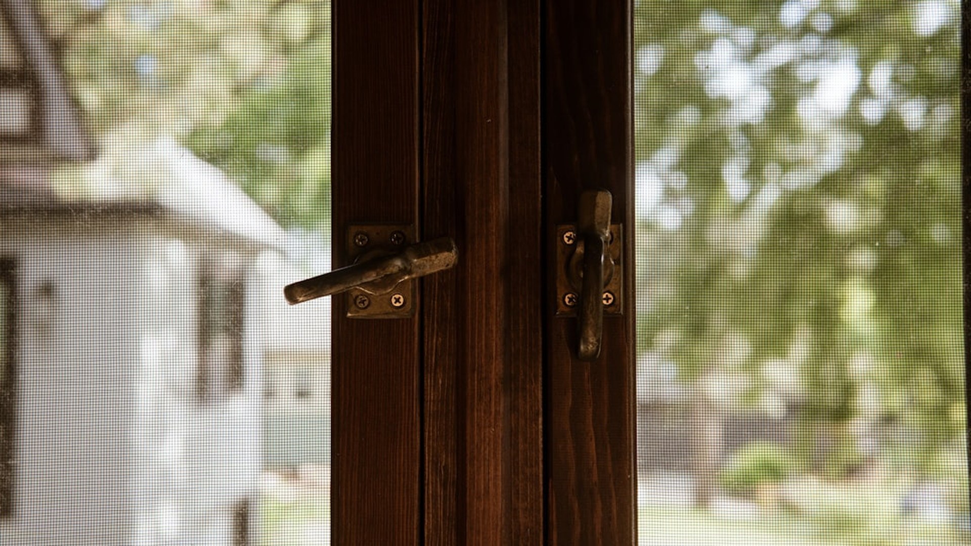 A woodgrain finish on a completed frame with its screen and hardware fitted: on uPVC profiles the colour is bonded to the profile, not painted on.