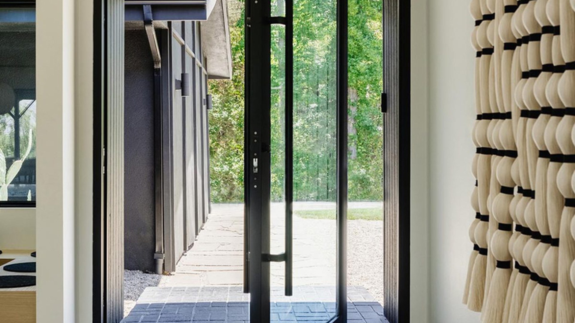 A custom aluminium pivot entrance door photographed mid-swing in a residential opening: the format specified where a feature entrance has to combine a full-height leaf with a sealed, weather-rated frame.