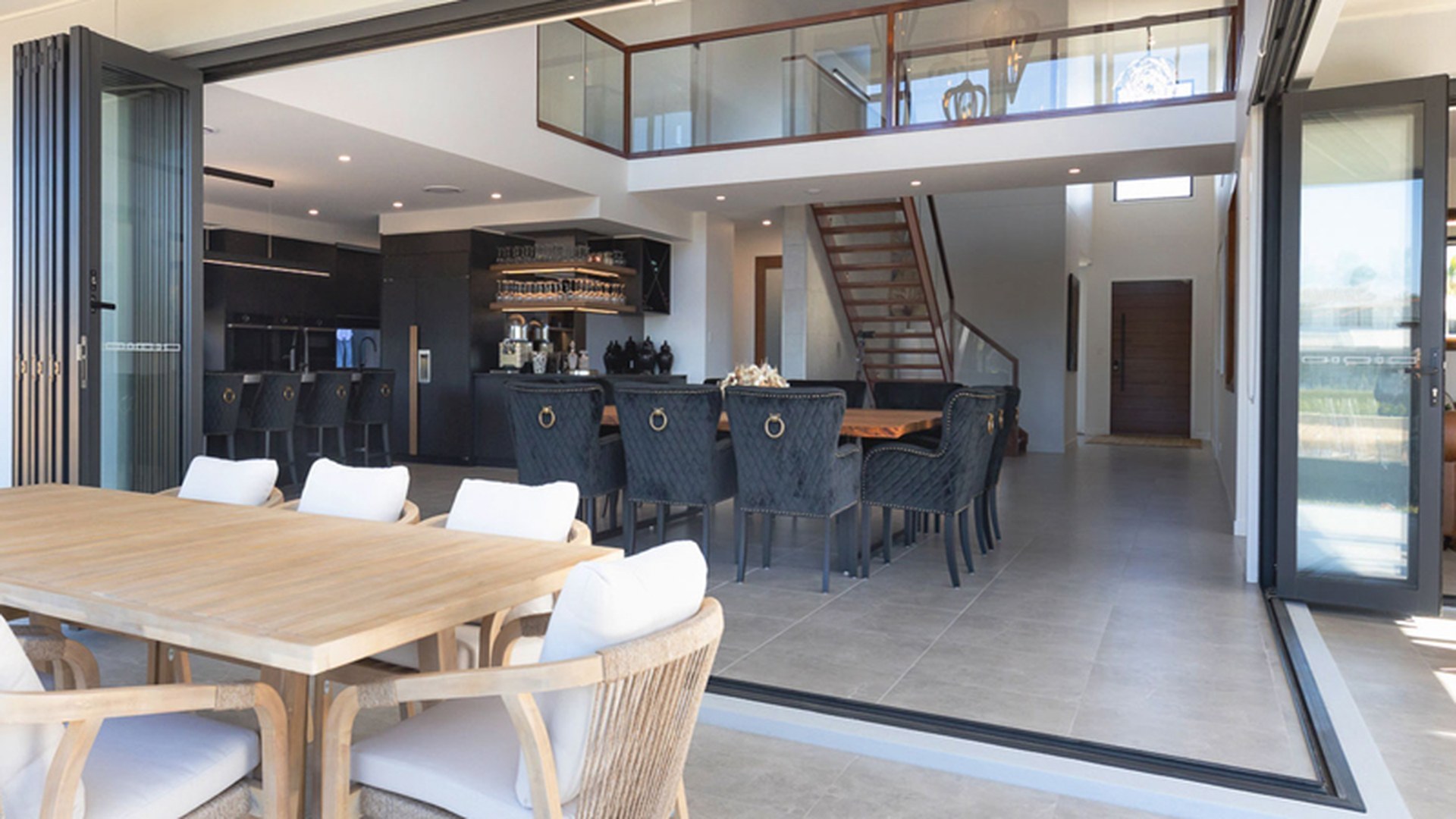 A large aluminium sliding door opening a living space onto a terrace, with the panels stacked to one side: the wide-span configuration most custom aluminium door projects are built around.