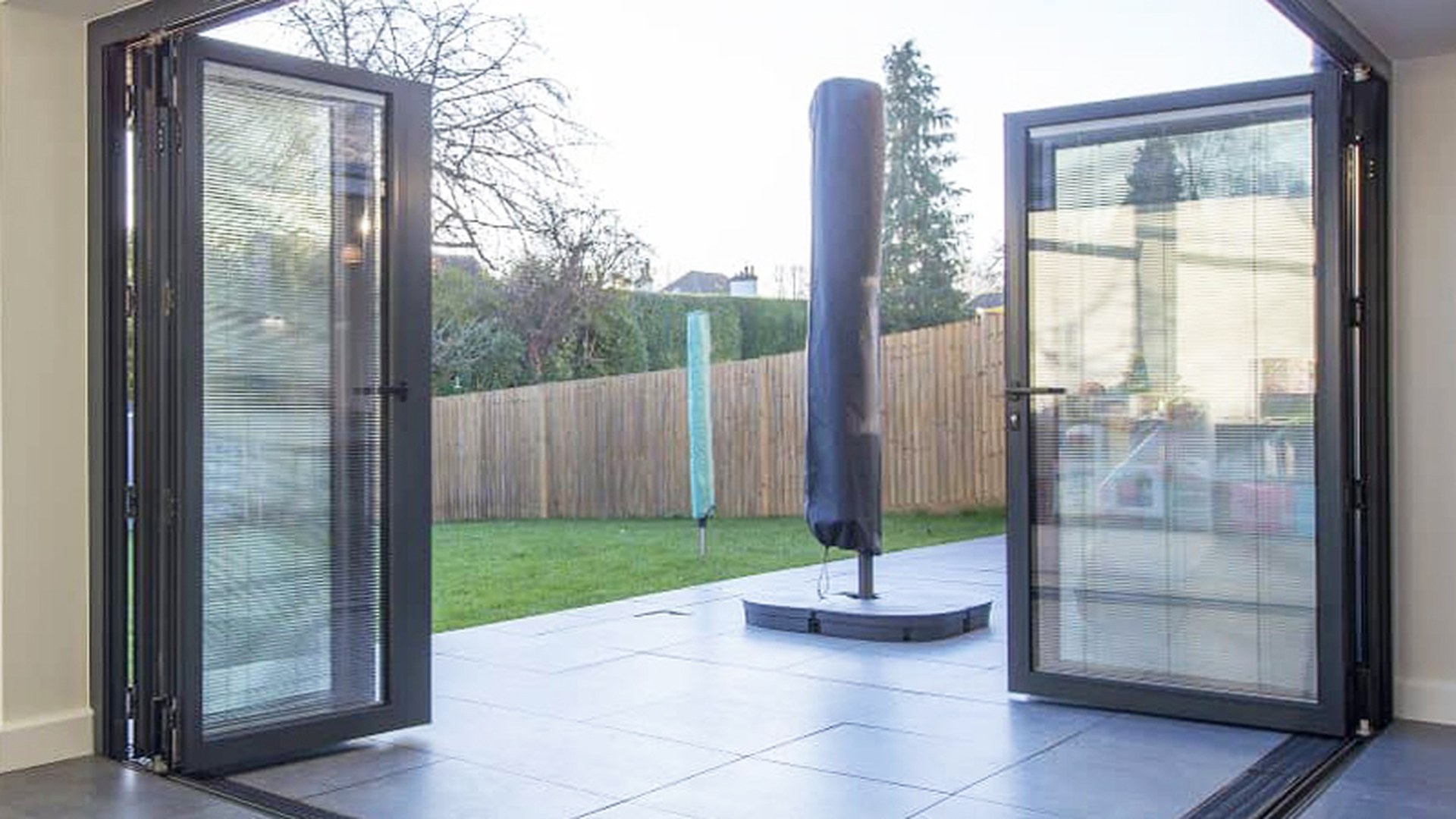 The corner junction of an aluminium folding door system photographed with the leaves open: the point where the frame, the running track and the floor detail have to be engineered as one assembly.