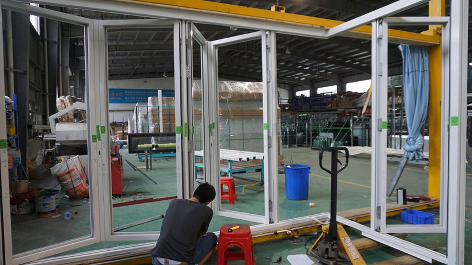 A completed multi-panel door set standing on trestles inside the workshop, operated and checked before packing: the stage where the frame, glazing and hardware are verified as one assembly.